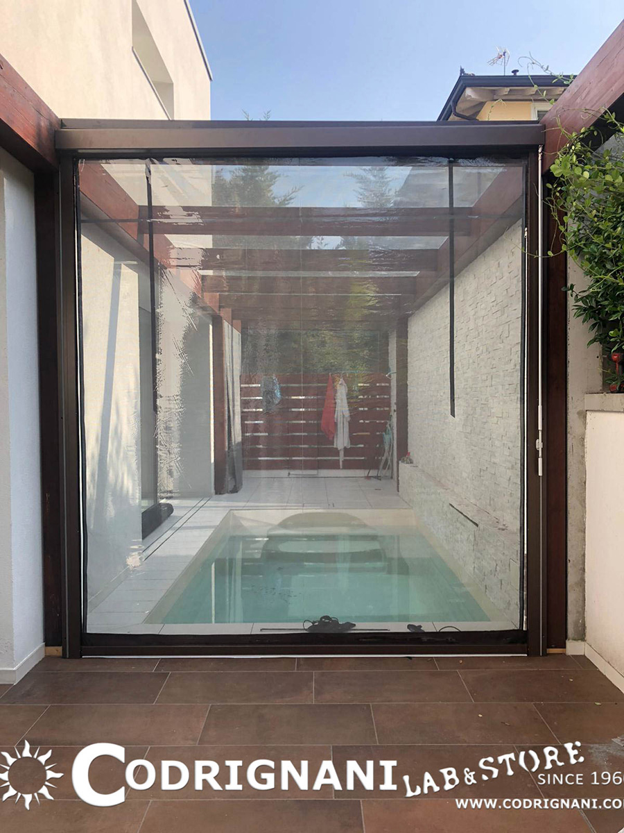 Chiusura patio esterno con piscina mediante tende tecniche in cristal trasparente